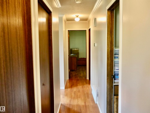 Hallway featuring wood-finish flooring, light-toned walls, crown molding, and recessed lighting - 5530 46 Street, Barrhead, AB 