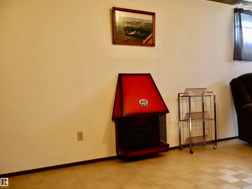 Freestanding red metal fireplace with a contrasting black base - 5530 46 Street, Barrhead, AB 