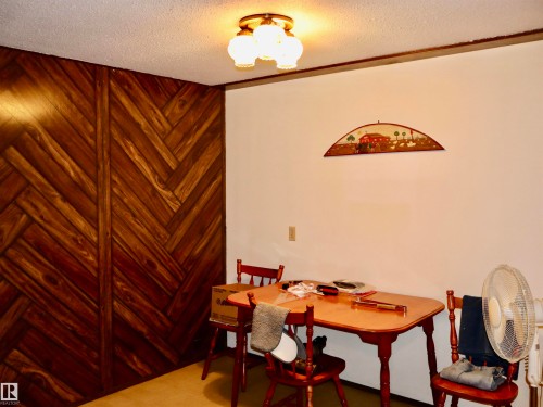 Herringbone wood-finish accent wall with a textured ceiling and a three-light flush mount fixture - 5530 46 Street, Barrhead, AB 