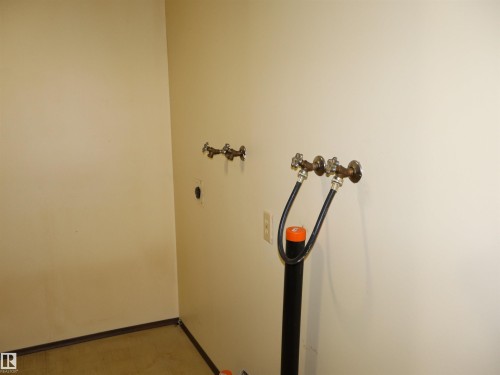 Dedicated utility area featuring wall-mounted water hookups, a utility drain, and light-toned wall finishes - 5530 46 Street, Barrhead, AB 
