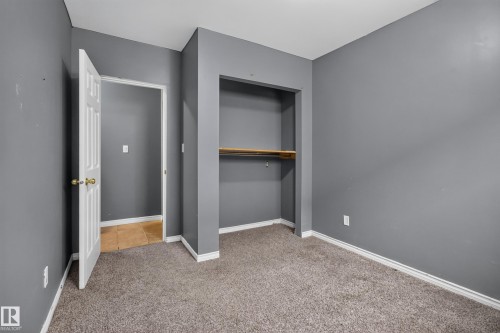 Carpeted interior room featuring neutral gray walls, white baseboards, and a built-in closet with a wood shelf - 9315 132A Avenue, Edmonton, AB 