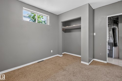 Room featuring neutral gray walls, light brown carpeting, and white baseboards - 9315 132A Avenue, Edmonton, AB 