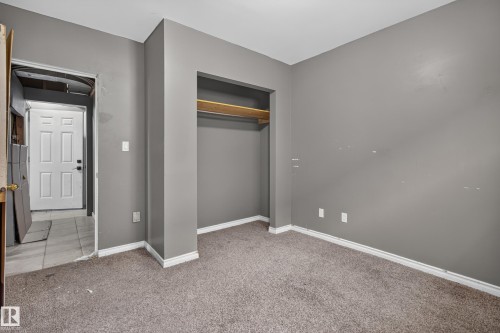 Carpeted room featuring neutral gray walls, white baseboards, and an open closet with a built-in shelf - 9315 132A Avenue, Edmonton, AB 