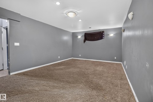 Carpeted room featuring gray walls, white baseboards, a ceiling fan with integrated lighting, recessed lighting, and wall-mounted sconces - 9315 132A Avenue, Edmonton, AB 