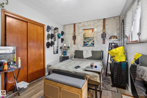 Bedroom with warm wood-finish flooring and a built-in closet featuring sliding wood doors - 9315 132A Avenue, Edmonton, AB 