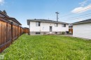 Spacious backyard with a horizontal plank wood fence, white vinyl siding, a gray shingle roof, and a detached white garage - 9315 132A Avenue, Edmonton, AB 