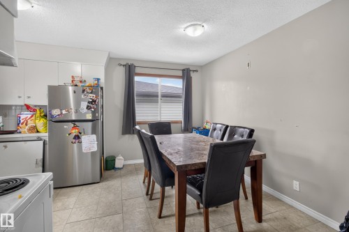 Kitchen area featuring white cabinetry, a stainless steel refrigerator, and tiled flooring - 9315 132A Avenue, Edmonton, AB 