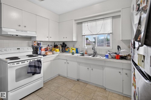 Kitchen featuring white cabinetry, tile backsplash, laminate countertops, and tile flooring - 9315 132A Avenue, Edmonton, AB 