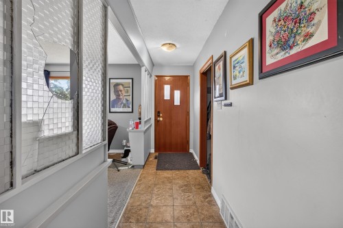 Entryway featuring wood-finish flooring, a solid wood-panel door with vertical window, and light grey walls - 9315 132A Avenue, Edmonton, AB 