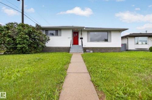 Ranch-style residence featuring white siding, a prominent red front door, and a concrete walkway - 9315 132A Avenue, Edmonton, AB 