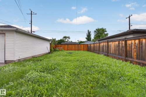 Expansive rear yard featuring a wood privacy fence and a detached garage with horizontal siding - 9315 132A Avenue, Edmonton, AB 