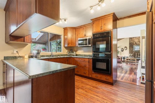 Kitchen featuring wood-finish flooring, wood cabinetry, a built-in double oven, and track lighting - 20515 5 Avenue Sw, Edmonton, AB 