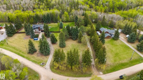 Expansive property featuring two distinct residences, mature evergreen trees, and a substantial grassy area - 20515 5 Avenue Sw, Edmonton, AB 