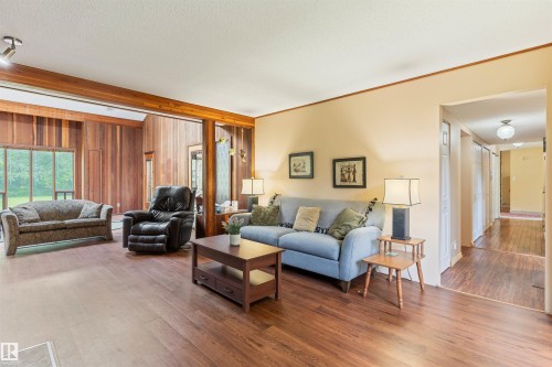 Spacious living area featuring wood-finish flooring, a neutral wall palette, and wood beam accents - 20515 5 Avenue Sw, Edmonton, AB 