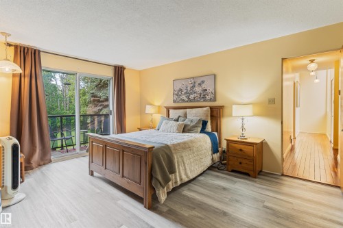 Bedroom featuring light wood-finish flooring, a sliding glass door to a private balcony, and warm-toned wall paint - 20515 5 Avenue Sw, Edmonton, AB 