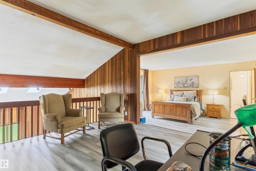 Open loft area featuring wood-finish flooring, wood paneled walls, and a wood railing overlooking a lower level - 20515 5 Avenue Sw, Edmonton, AB 