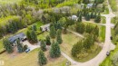 Expansive residential property featuring multiple structures, mature evergreen trees, and verdant landscaping - 20515 5 Avenue Sw, Edmonton, AB 