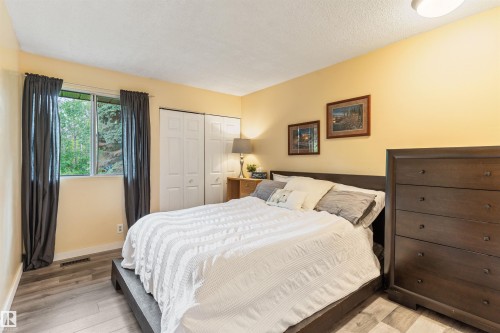 Bedroom featuring light wood-finish flooring and a window with a green tree backdrop - 20515 5 Avenue Sw, Edmonton, AB 