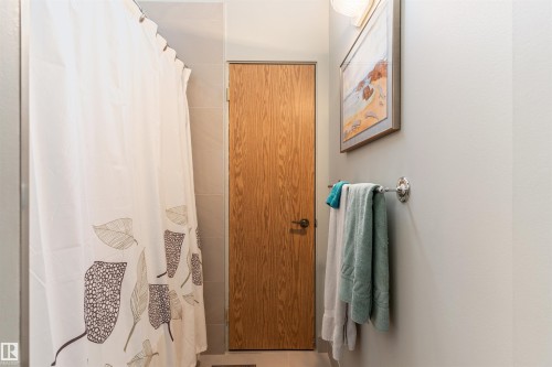 Bathroom featuring a light wood-finish door with a dark handle, a polished chrome towel bar, and neutral painted walls - 20515 5 Avenue Sw, Edmonton, AB 