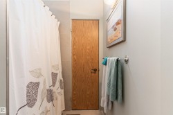 Bathroom featuring a light wood-finish door with a dark handle, a polished chrome towel bar, and neutral painted walls - 