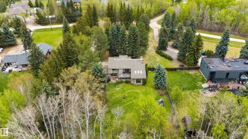 Expansive lot featuring a multi-story residence with a brown shingle roof, surrounded by mature evergreen and deciduous trees - 20515 5 Avenue Sw, Edmonton, AB 