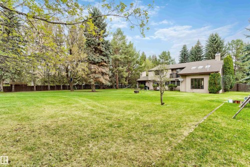 Expansive rear lawn with mature perimeter trees and a privacy fence - 20515 5 Avenue Sw, Edmonton, AB 