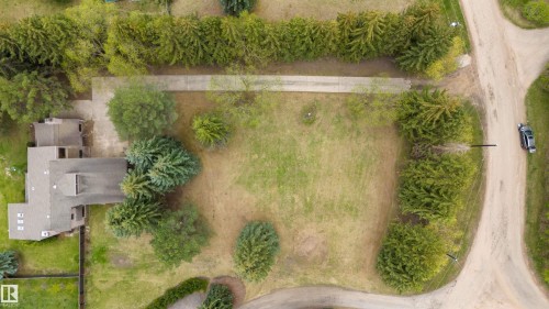 Expansive green space featuring mature trees and a substantial concrete driveway - 20515 5 Avenue Sw, Edmonton, AB 