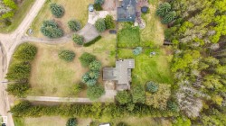 Expansive property featuring a central residence with a gabled roofline, surrounded by mature trees and manicured lawns - 