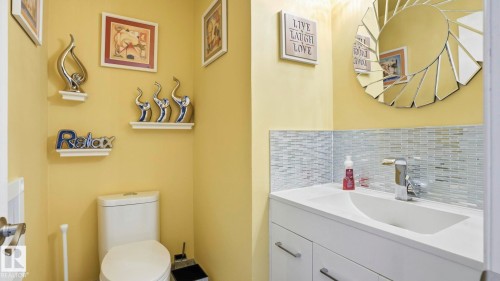 Powder room featuring a white single vanity with a curved basin, chrome faucet, and a mosaic tile backsplash - 1827 36 Street Nw, Edmonton, AB 
