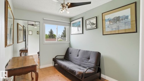 Light-filled room featuring wood-finish flooring, a ceiling fan with integrated lighting, and a window with blinds - 1827 36 Street Nw, Edmonton, AB 