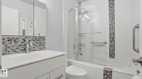 Bathroom featuring a modern vanity with integrated sink, chrome faucet, mosaic tile backsplash, and a medicine cabinet - 1827 36 Street Nw, Edmonton, AB 