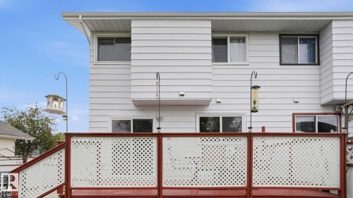 Exterior featuring white vinyl siding, multiple windows, and a lattice-paneled deck with brown railings - 1827 36 Street Nw, Edmonton, AB 