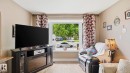 Living space featuring wood-finish flooring, a large window, and light-toned wall paint - 1827 36 Street Nw, Edmonton, AB 