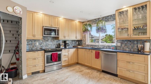 Kitchen featuring light wood cabinetry, stone countertops, and stainless steel appliances - 1827 36 Street Nw, Edmonton, AB 