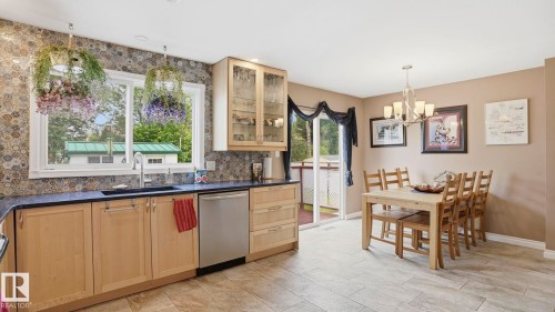 Kitchen featuring light wood cabinetry, a dark countertop, stainless steel appliances, and a patterned backsplash - 1827 36 Street Nw, Edmonton, AB 