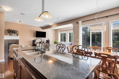 Kitchen island featuring a double basin stainless steel sink, a high-arc faucet, and a stone-finish countertop - 18 Voleta Crest, Spruce Grove, AB 