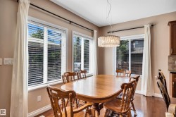 Dining area featuring wood-finish flooring, multiple windows with blinds, and a contemporary drum pendant light - 