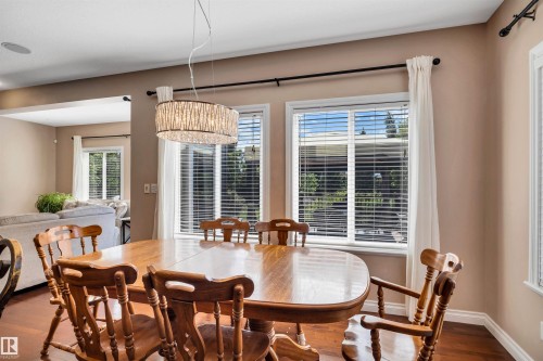 Dining area featuring wood-finish flooring, two large windows, and a contemporary crystal chandelier - 18 Voleta Crest, Spruce Grove, AB 