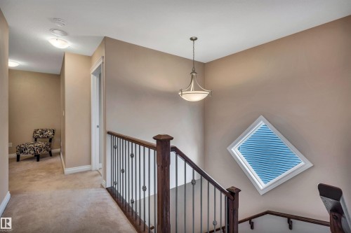 Staircase with dark wood newel posts and handrails, featuring wrought iron balusters - 18 Voleta Crest, Spruce Grove, AB 