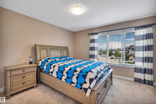 Carpeted room featuring a large window with white blinds and striped curtains, light beige wall paint, and a ceiling-mounted light fixture - 18 Voleta Crest, Spruce Grove, AB 