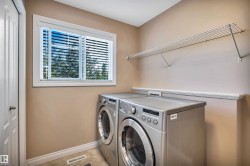 Dedicated laundry area featuring a white framed window, horizontal blinds, and a built-in wire shelf - 