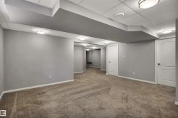 Carpeted interior space featuring light gray walls, white baseboards, and white paneled doors - 