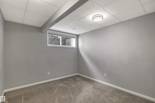 Carpeted room featuring light gray walls, a drop ceiling, and white baseboards - 18 Voleta Crest, Spruce Grove, AB 