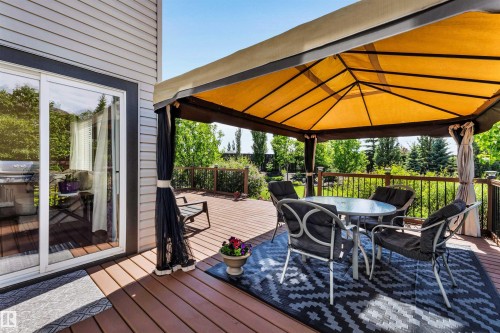 Expansive outdoor deck featuring wood-finish flooring, a covered gazebo, and a dark wood railing - 18 Voleta Crest, Spruce Grove, AB 