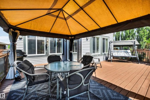 Spacious outdoor deck featuring wood-finish flooring, dark metal railings, and a gazebo with a yellow canopy - 18 Voleta Crest, Spruce Grove, AB 