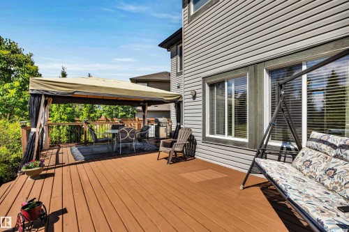 Spacious outdoor deck featuring brown wood-finish flooring, a covered patio area, and a horizontal siding exterior - 18 Voleta Crest, Spruce Grove, AB 