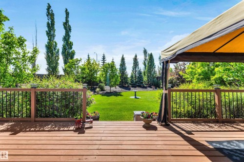 Spacious wood-finish deck with a built-in gazebo, black baluster railing, and post cap lighting - 18 Voleta Crest, Spruce Grove, AB 