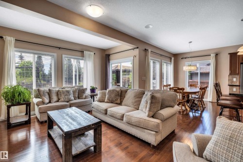 Open-concept living space featuring wood-finish flooring, recessed lighting, and multiple large windows with horizontal blinds - 18 Voleta Crest, Spruce Grove, AB 
