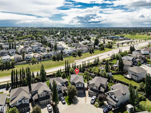 Overhead aerial perspective showcasing a residential area with a prominent two-story home featuring a dark shingle roof and an attached two-car garage - 18 Voleta Crest, Spruce Grove, AB 