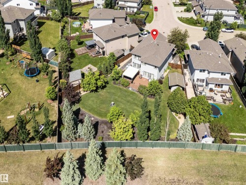 Rear elevation featuring a multi-level deck with a retractable awning, surrounded by a manicured lawn and mature landscaping - 18 Voleta Crest, Spruce Grove, AB 